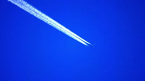 Airplane flying in clear blue sky leaving long white contrail Stock Footage 345987625