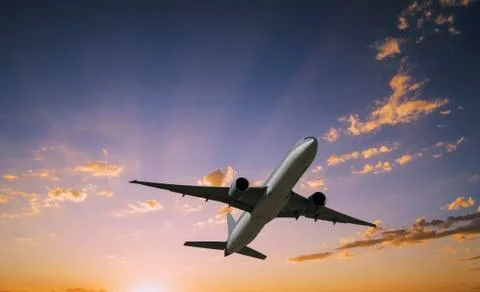 Airplane flying in dramatic sunset sky Stock Photos