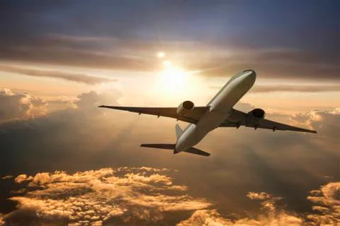 Airplane flying in dramatic sunset sky Stock-Fotos
