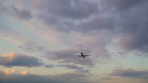 Airplane flying in evening cloudy sky. Aircraft gaining height at sunset sky Stock Footage 117371808