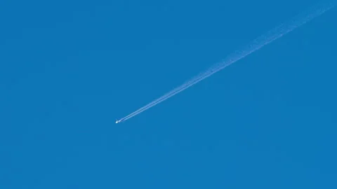 Airplane flying high in clear blue sky leaving white contrail Stock Footage 346352007