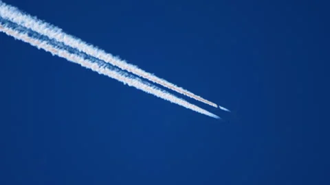 Airplane flying high in deep blue sky leaving double contrails Stock Footage 346356061