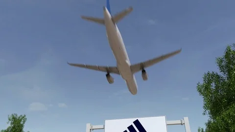 Airplane flying over advertising billboard with Adidas inscription and logo Stock Footage