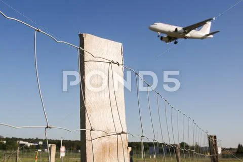 Airplane flying over barbed wire Stock Photos