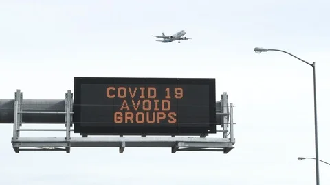 Airplane Flying Over COVID 19 Warning Road Sign Stock Footage