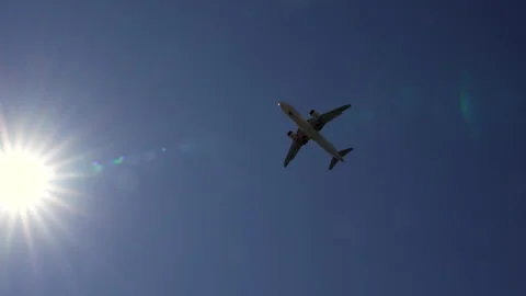 Airplane flying overhead passing the sun Stock Footage 280392980