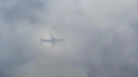Airplane flying through clouds casting a glory shadow effect seen from above. Stock Footage 337450218