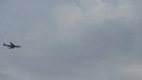 Airplane flying through the cloudy sky. Soaring plane in silhouette with a blue 库存影片 104483439