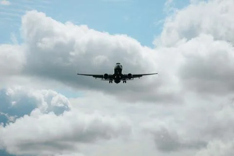 Airplane flying through a cloudy sky, with a clear view of the aircraft's u.. Stock Photos