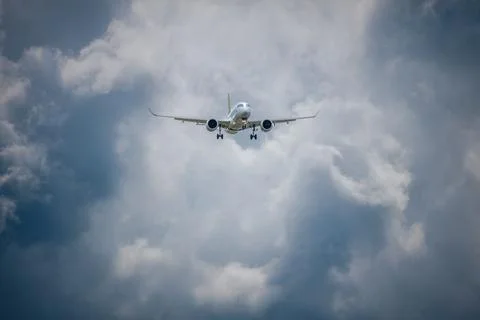 Airplane flying through cloudy sky with dramatic cloud formations, showcasi.. Foto stock