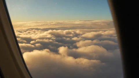 Airplane flying through white and golden clouds on a sunny day. Airplane window  Stock Footage 268447328