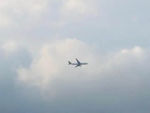 Airplane Flying Under Clouds Stock Photos