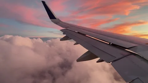 Airplane flys over white fluffy clouds during sunset Video stock 249787516