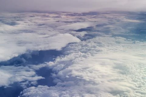 Airplane illuminator view on fluffy clouds and blue sky. Stock Photos