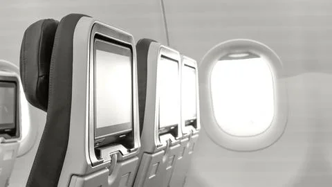Airplane interior featuring empty passenger seats with personal screens and a Stock Photos