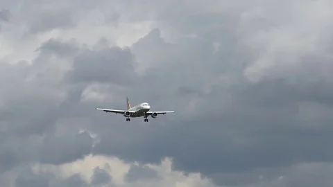Airplane landing in front of clouds Stock Footage 76564541