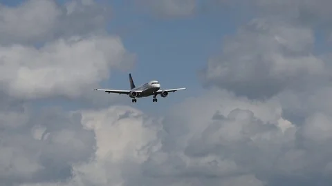 Airplane landing in front of clouds Stock Footage 76565477