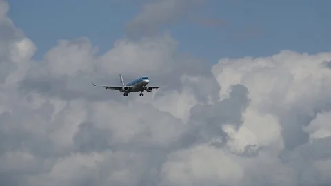 Airplane landing in front of clouds Stock Footage 76565573