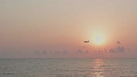 Airplane landing in the rays of the setting sun over the sea, summer travel. Stock Footage 168372491