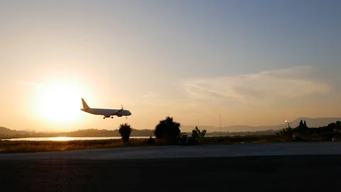 Airplane landing on runway two second before touchdown in side view at sunset Stock Footage 112354373