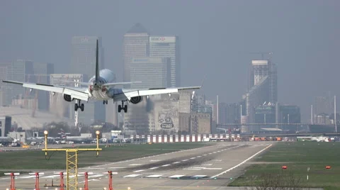 Airplane lands at London City airport, England, Canary Wharf in background Stock Footage