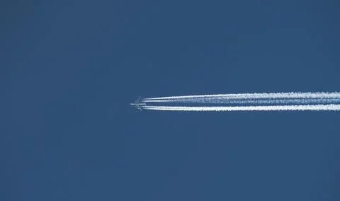 Airplane with a long reverse trail in the blue sky Foto stock