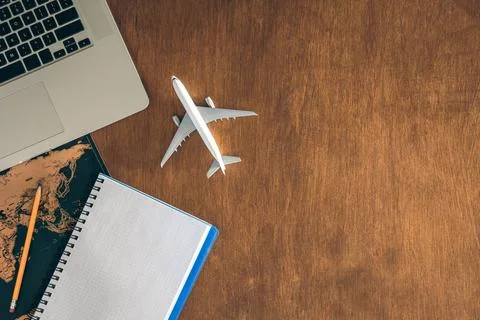 Airplane miniature, notepad, World map and laptop on a wooden table. Stock Photos