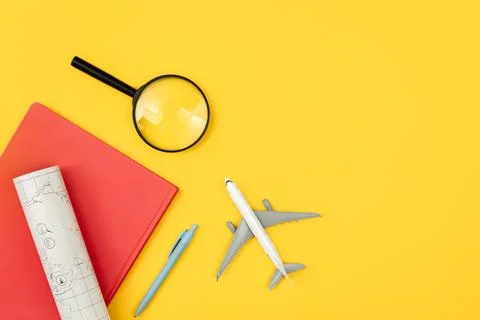 Airplane model, notebook, map and magnifier on yellow background, flat lay. Stock Photos