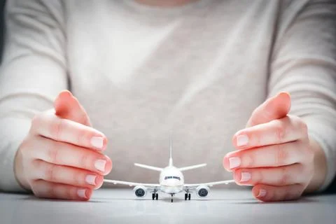 Airplane model surrounded by hands in gesture of protection. Concept of aircr Stock Photos