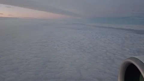 An airplane moves above a cloud layer during a sunset flight over Europe. View f Vídeo Stock 335317712