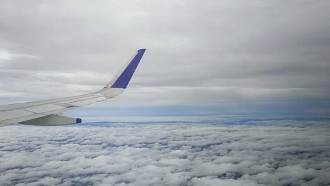 Airplane moving through clouds and blue sky, view from window, FullHD 1080p Stock Footage 138680435