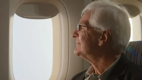 Airplane passenger, older man looking out the window of airplane, zoom in Stock Footage 233640115