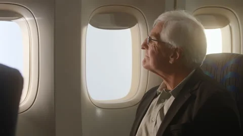 Airplane passenger, older man looking out the window of airplane Stock Footage 233739803