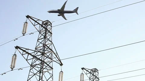 Airplane passing up the electrical towers Stock Footage 11162665