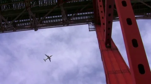 Airplane passing flying over a red bridge Stock Footage 48528837