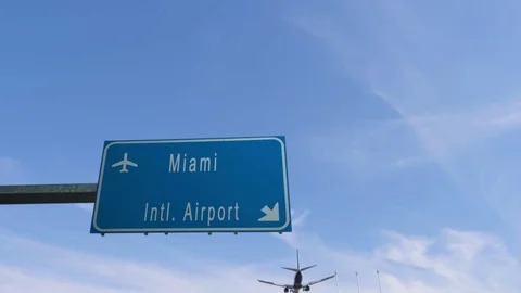 Airplane passing over miami airport sign Stock Footage