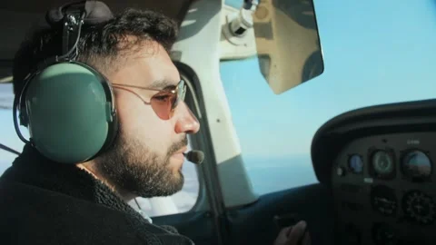 Airplane pilot in flight close-up daylight.Young beard man wearing headphones Stock Footage 253240762