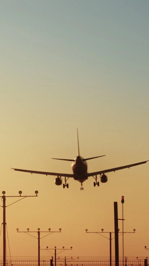 An airplane is shown landing at sunset in a vertical video while approaching the Stock Footage 276575650