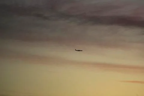 Airplane in sky with clouds sunset evening colors Stock Photos