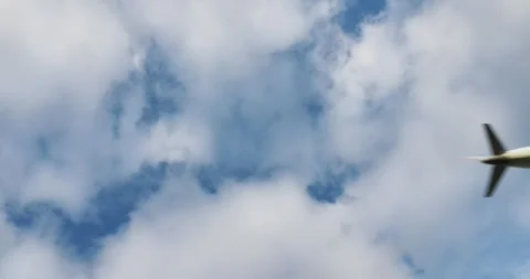 Airplane soaring overhead, creating a condensation trail through fluffy clouds Stock Footage 300617532
