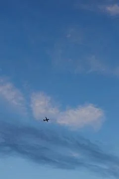 An airplane soars through the evening sky Stock Photos