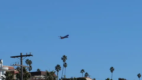 Airplane taking off from LAX over the roofs of homes on the beach Stock Footage 145829920