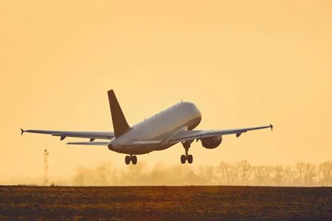 Airplane taking off at sunset Stock Photos