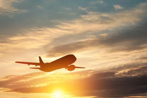 Airplane taking off at the sunset sky. Stock Photos