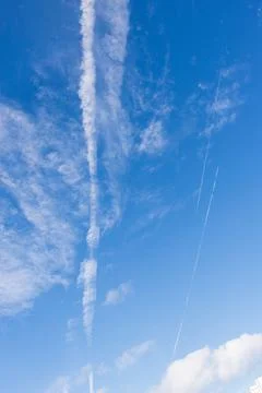 Airplane trail in a blue sky with clouds Stock Photos