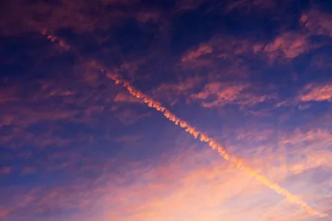 Airplane trail in sunset Stock Photos