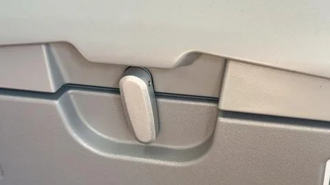 Airplane tray lock close-up featuring gray plastic surface and lever mechan.. Stock Photos