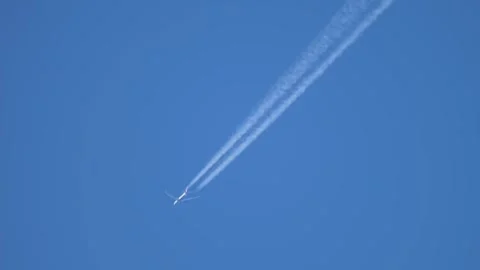 Airplane viewed from below creating twin white trails in deep blue sky, upward Stock Footage 340326181
