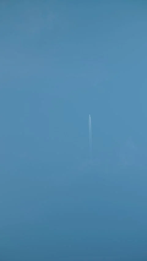 Airplane with a white trail in a clear blue sky Stock Footage 316425108