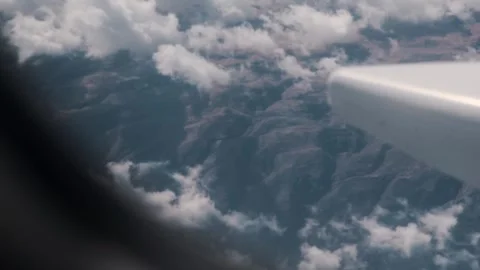 Airplane window and wing in the air and high mountains with snow and clouds Video stock 312336301